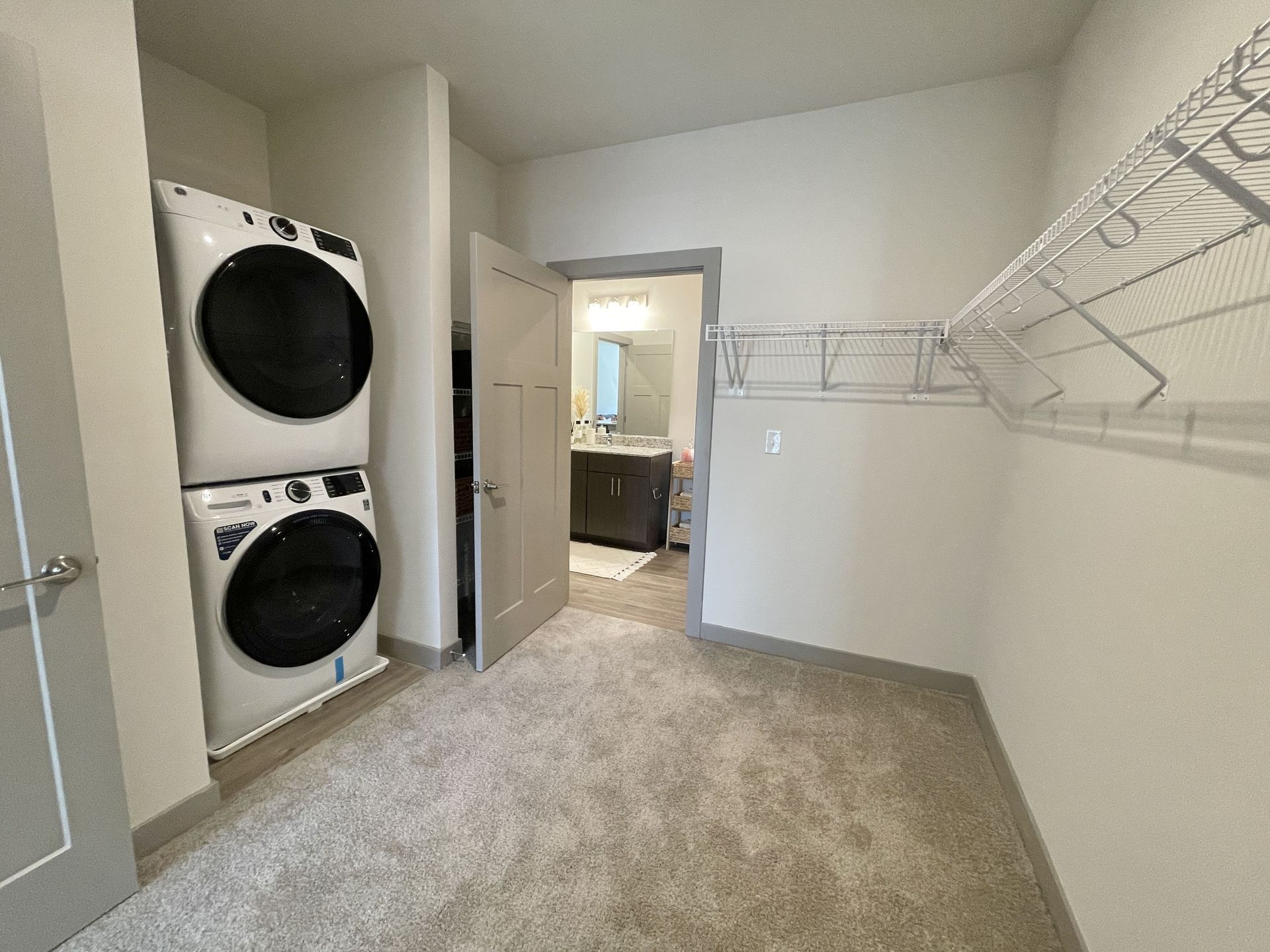 A walk in closet with a washer and dryer stacked on top of each other.