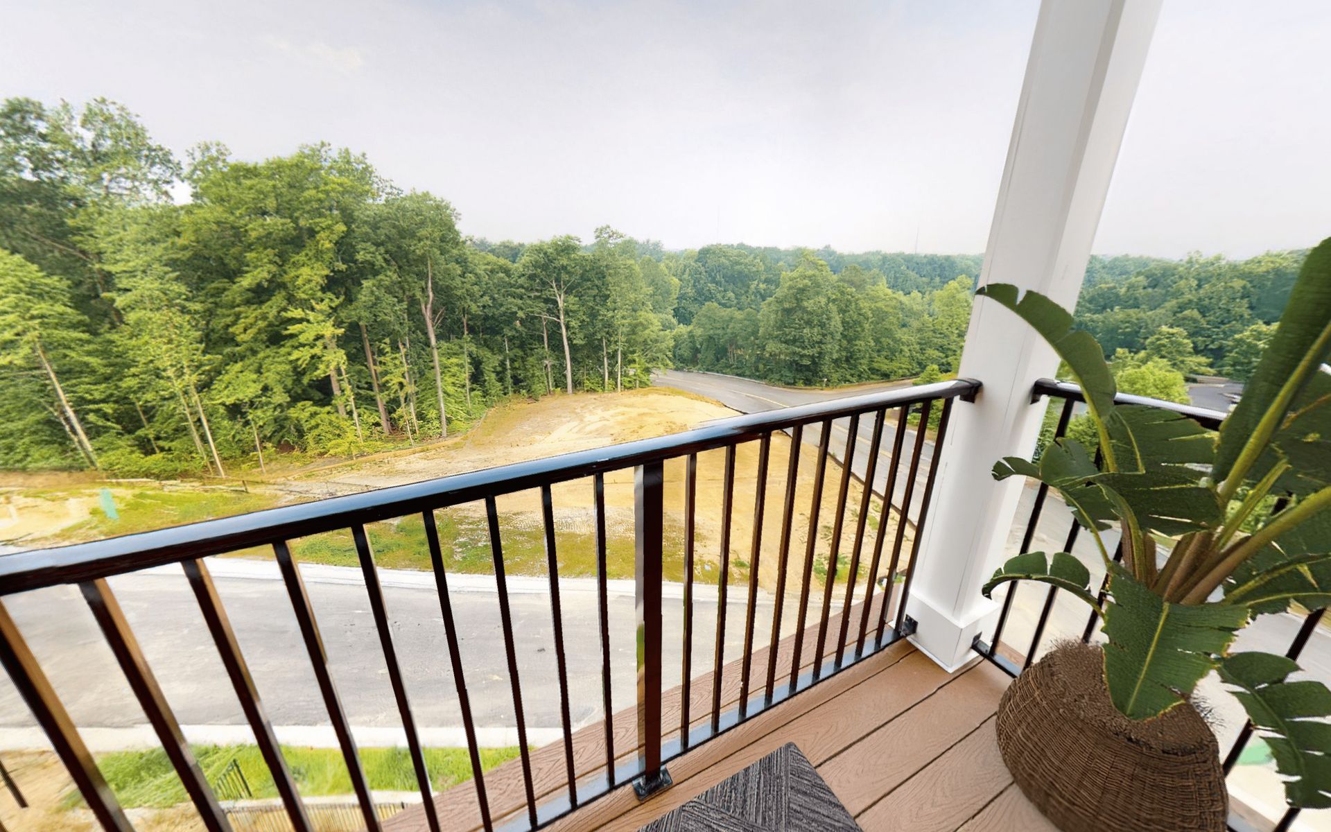 A balcony with a view of a forest and a road.