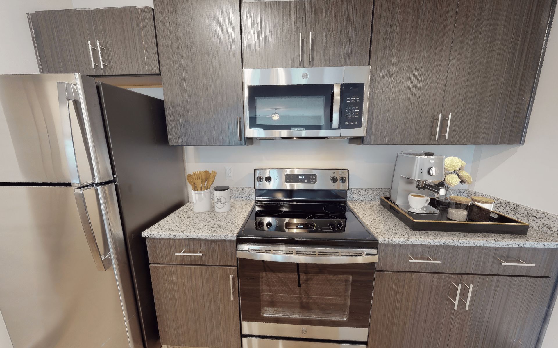 A kitchen with a stove , microwave , refrigerator and sink.