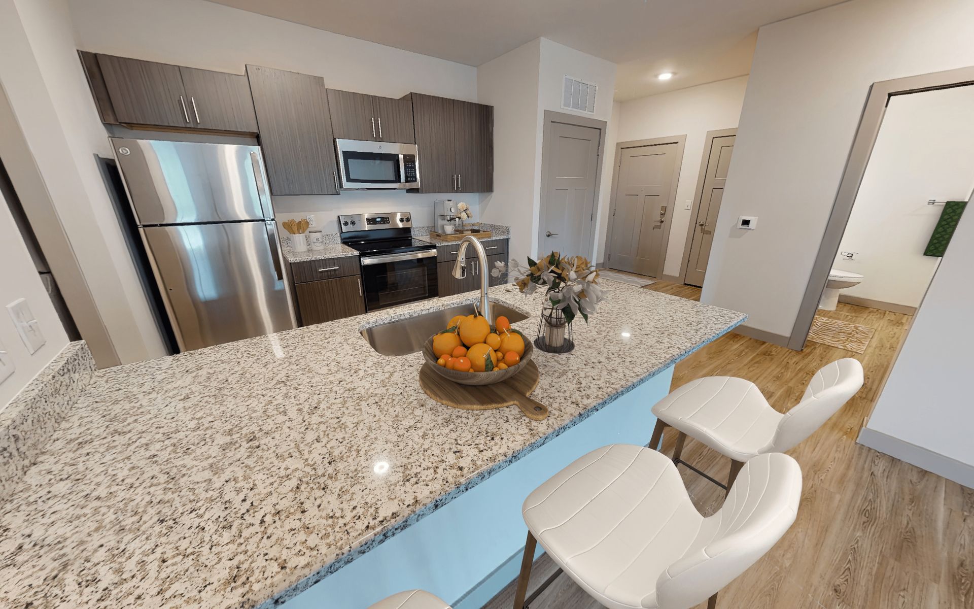 A kitchen with granite counter tops , stainless steel appliances , a refrigerator and a sink.
