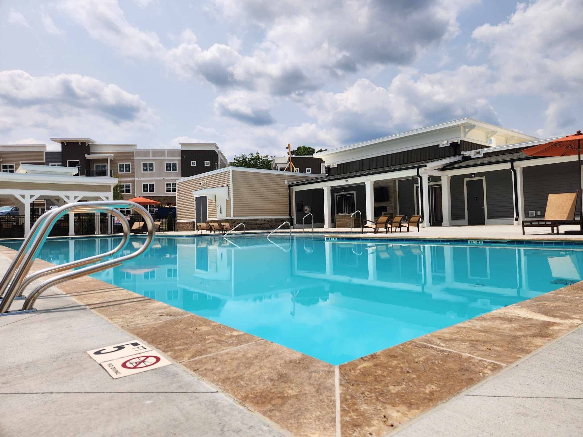 A large swimming pool is surrounded by chairs and umbrellas.