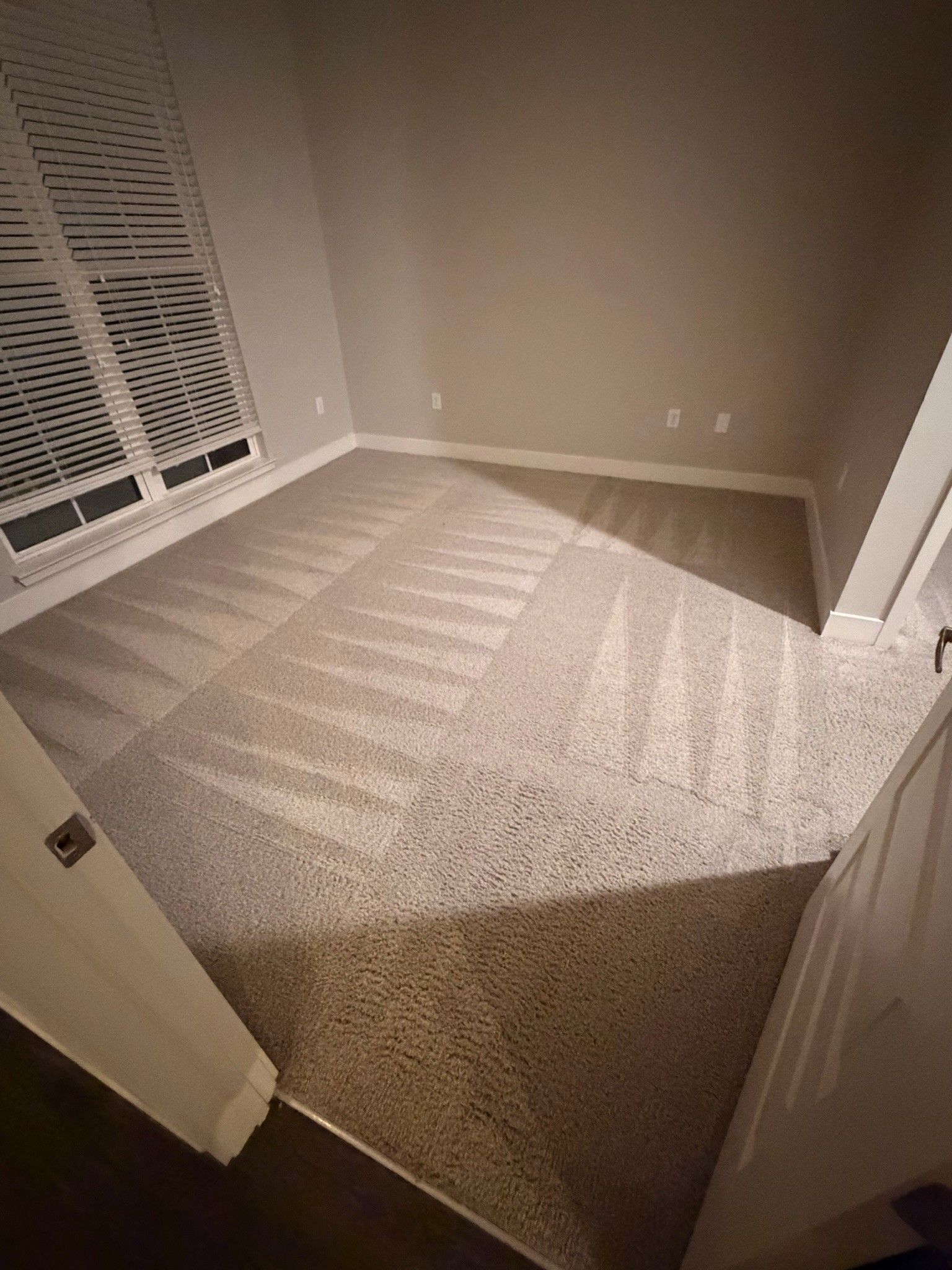 Empty carpeted bedroom with open closet doors and sunlight casting striped shadows on the floor
