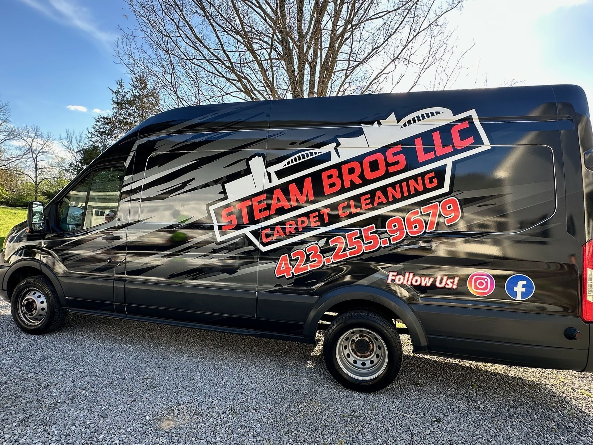 Black work van with STEAM BROS LLC carpet cleaning logo and contact info parked outdoors
