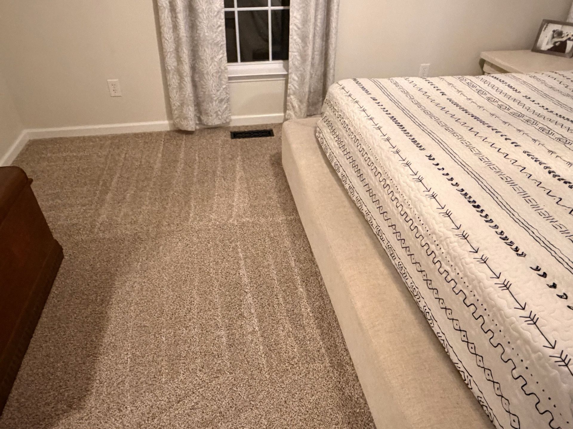 Bedroom with carpeted floor, bed on right, dresser on left, and window with curtains at the far end.