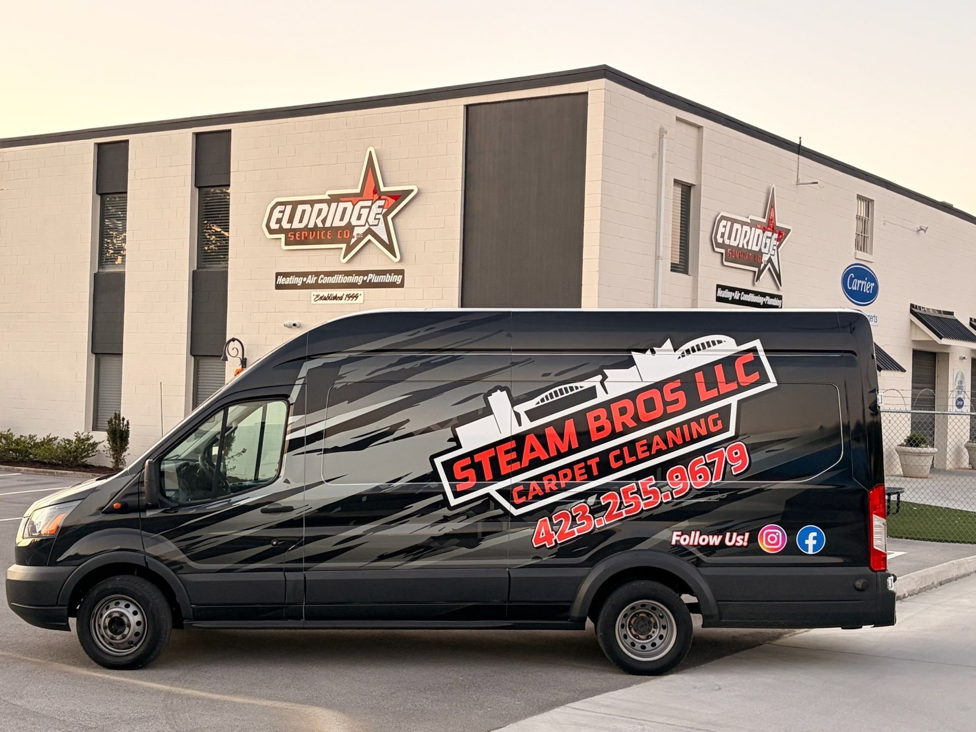 Black service van with Steam Bros LLC cleaning logo parked outside a warehouse building