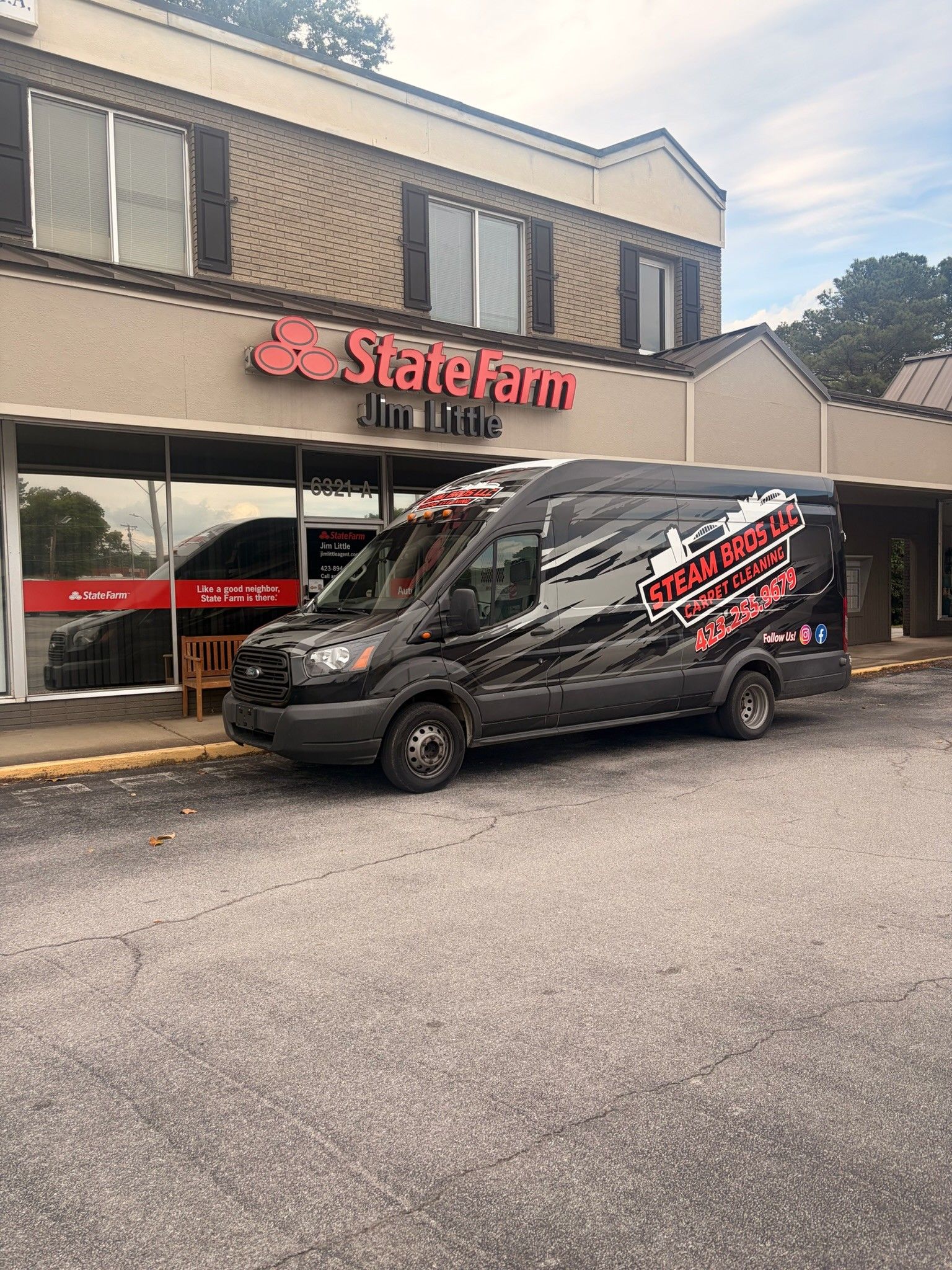 Black State Farm van parked in front of a State Farm office on a city street.