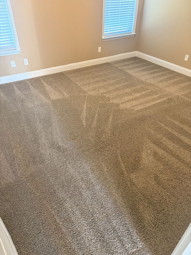 Worker vacuuming a red patterned rug in a workshop or rug-cleaning shop