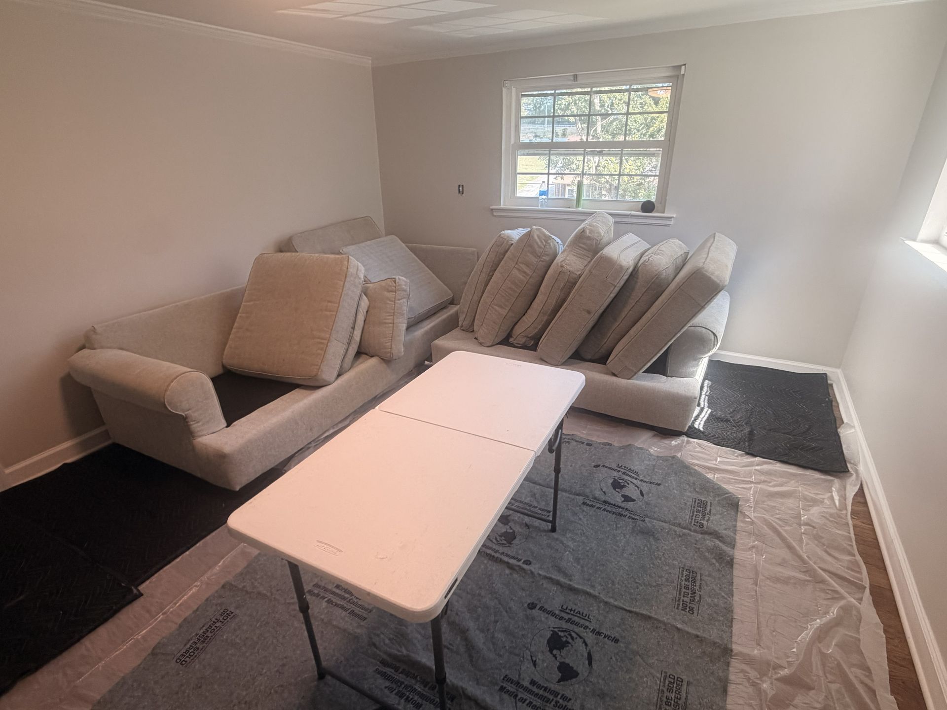 Small living room with two beige sofas, a white coffee table, and a window in the back wall.