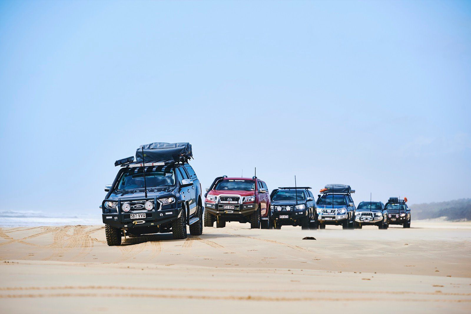 Several 4x4 Vehicles Driving on a Sandy Beach Under a Blue Sky — TJM Wagga Wagga In Ashmont, NSW