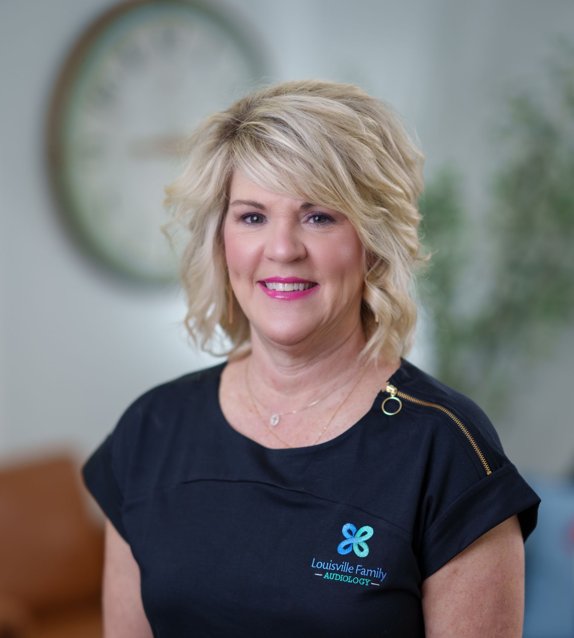A woman wearing a black shirt with a butterfly on the front is smiling for the camera.