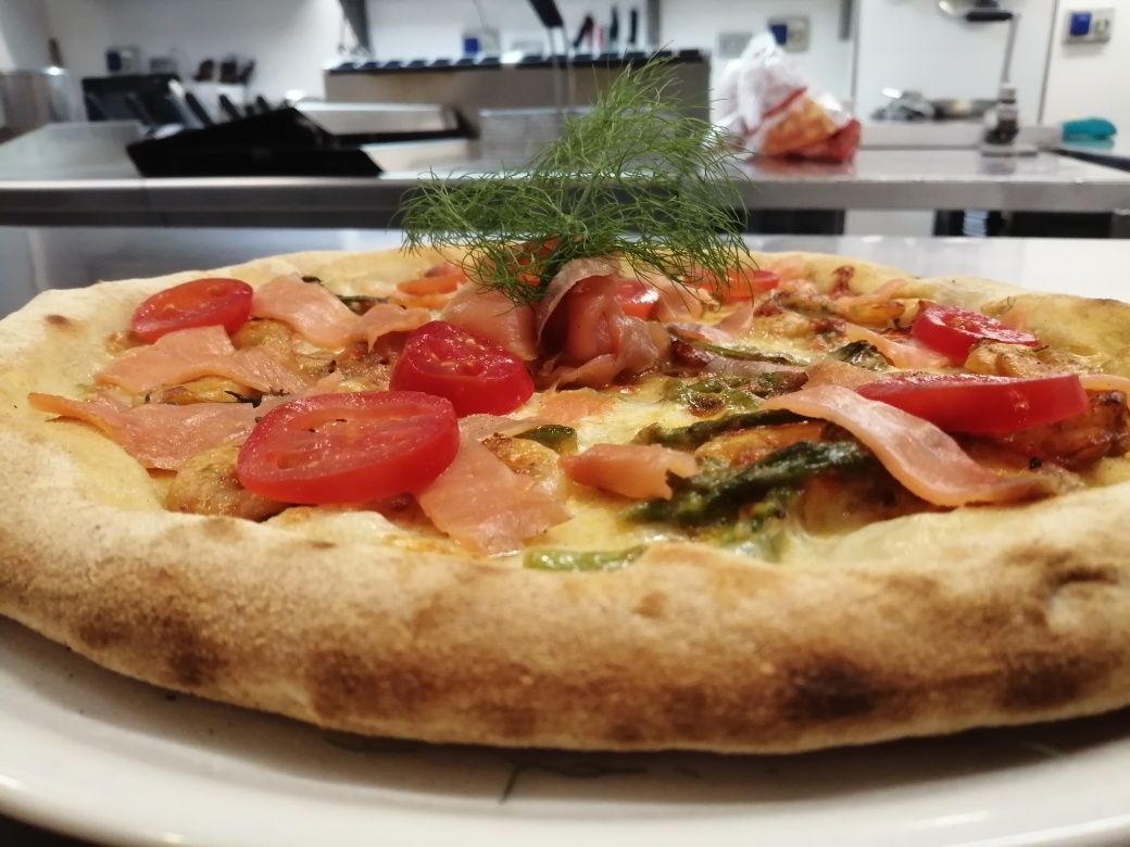 Una pizza con pomodori e salmone affumicato su un piatto bianco