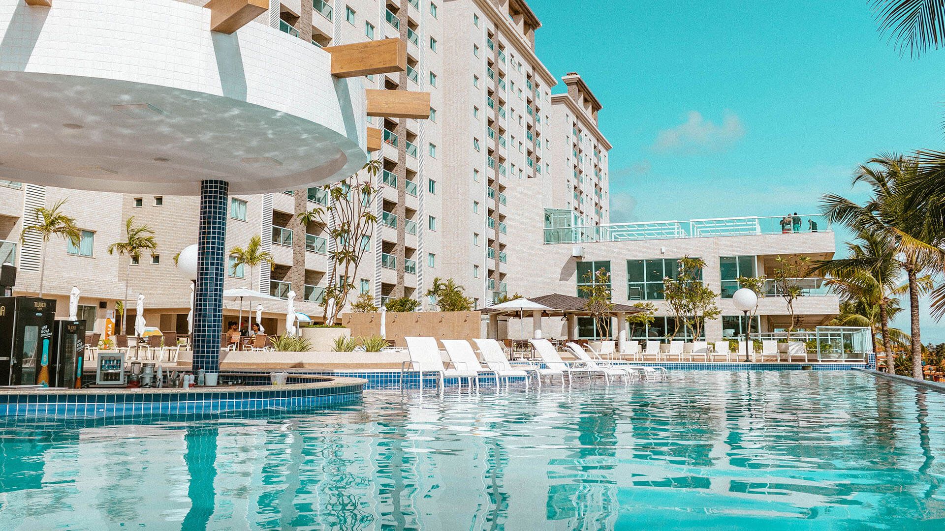 Uma grande piscina com um bar no meio em frente a um hotel.