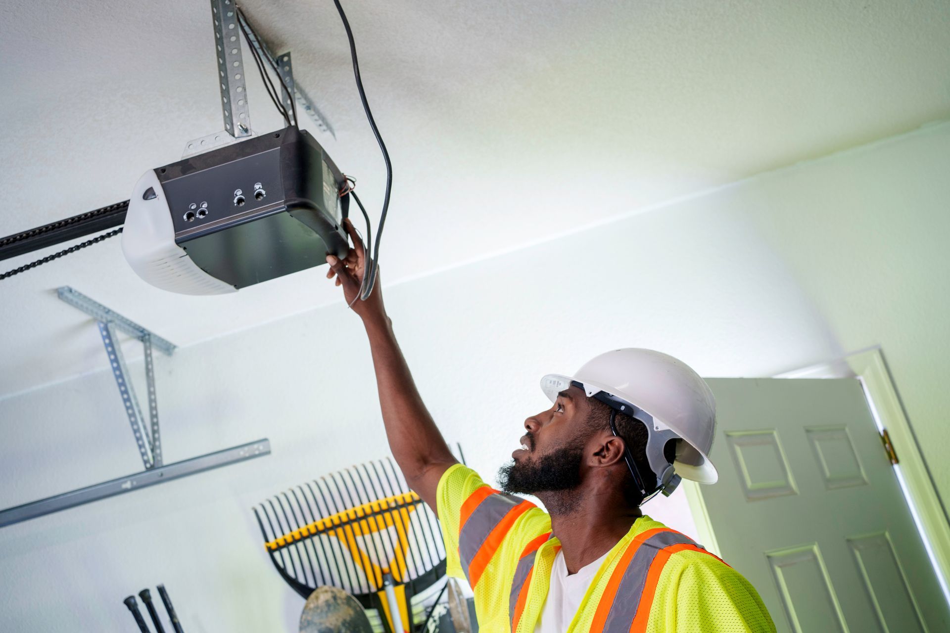 A man engaged in garage door opener repair, using tools to troubleshoot the device.