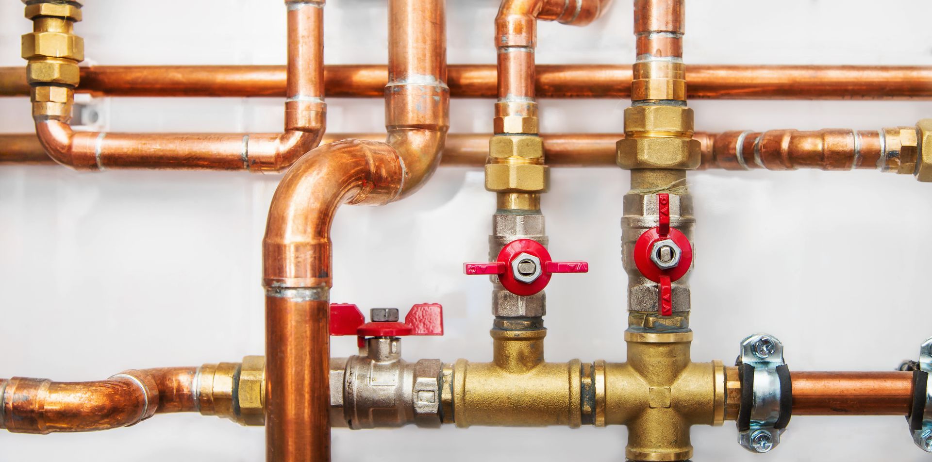 Copper plumbing pipes with red shutoff valves and brass fittings in a wall installation Copper plumbing pipes with red shutoff valves and brass fittings in a wall installation