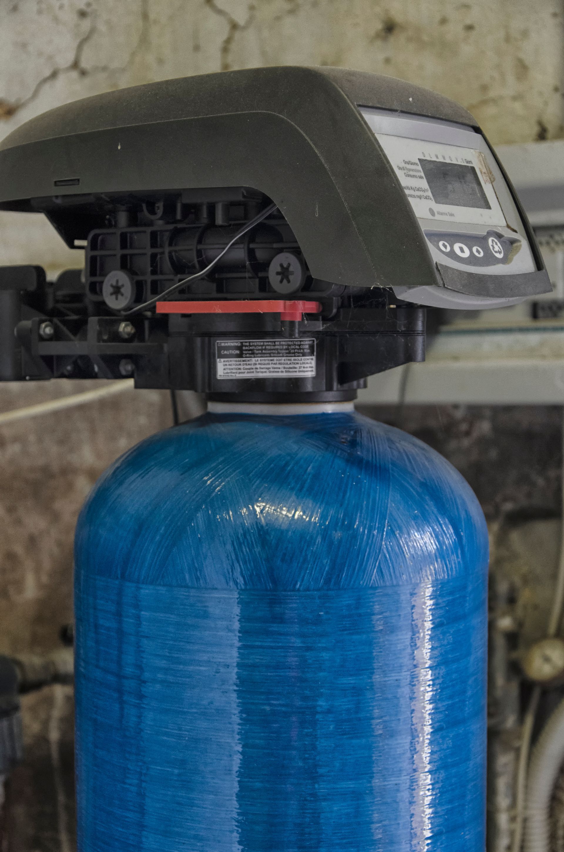 Blue water softener tank with black control valve against a wall Blue water softener tank with black control valve against a wall