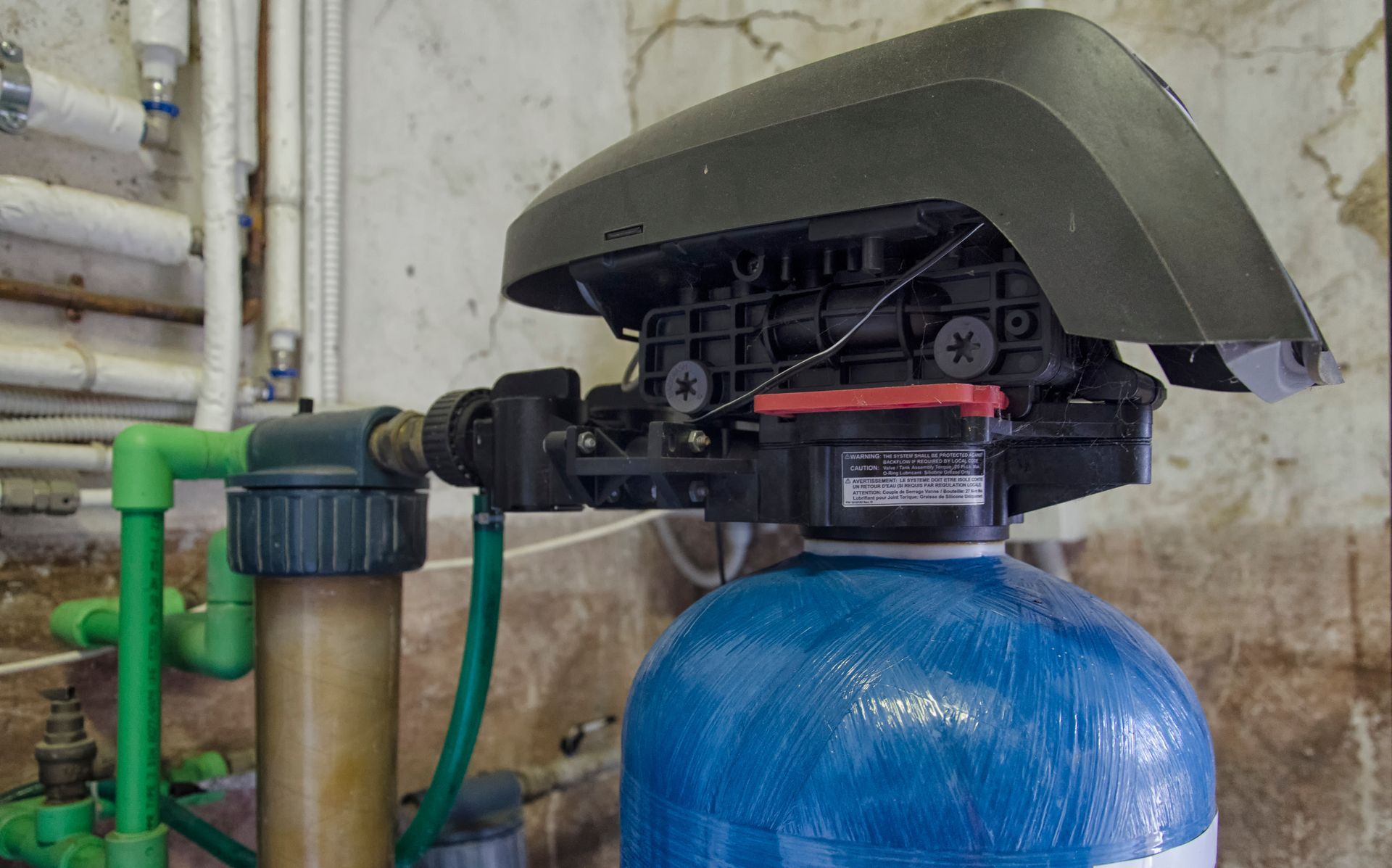 Plumber repairing a toilet pipe connection under a sink with tools in a tiled bathroom