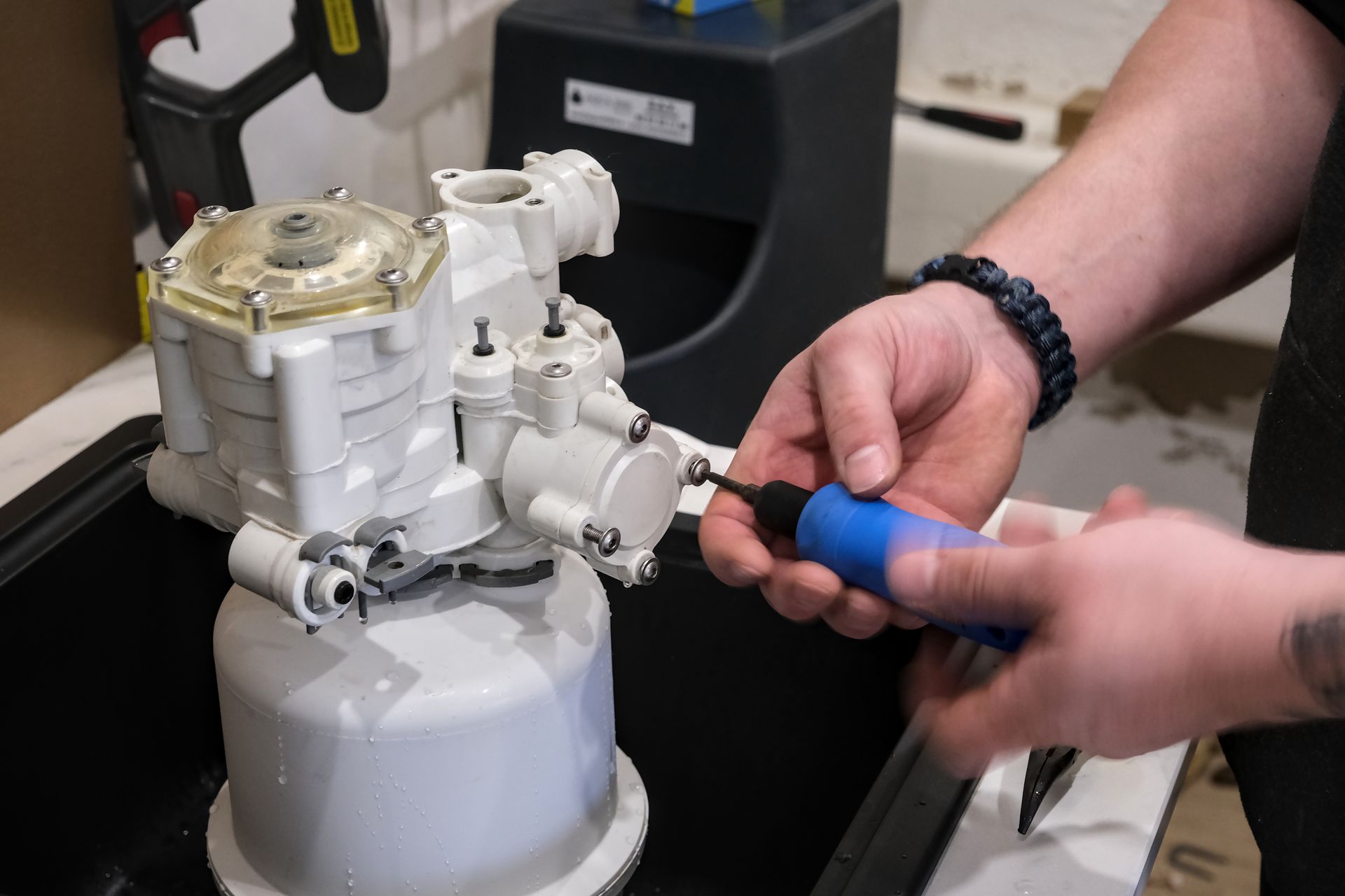 Hands tightening a blue-handled tool on a metal cylinder valve in a workshop Hands tightening a blue-handled tool on a metal cylinder valve in a workshop
