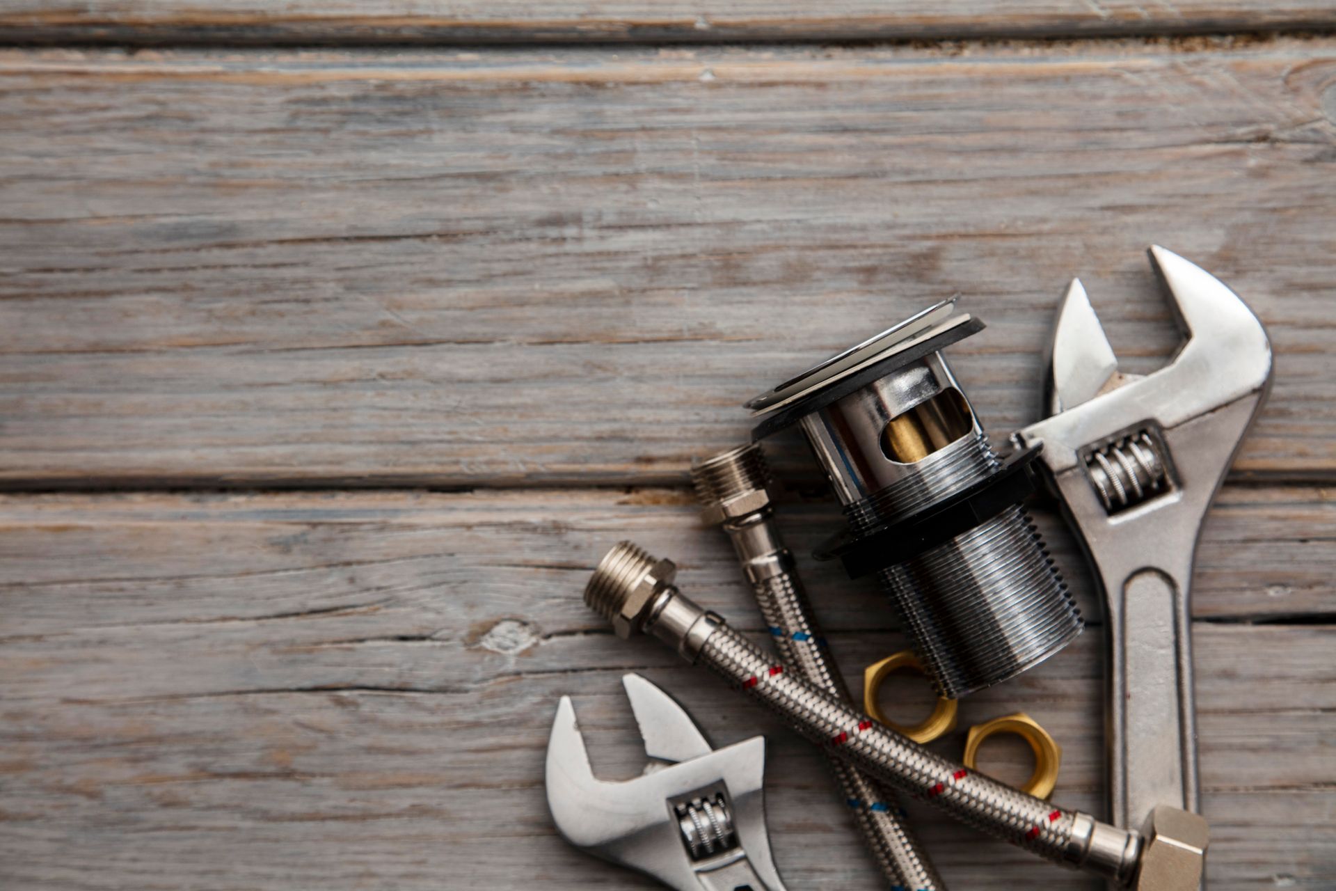 Fishing tools and gear on a weathered wooden surface, including lures, pliers, and wrenches
