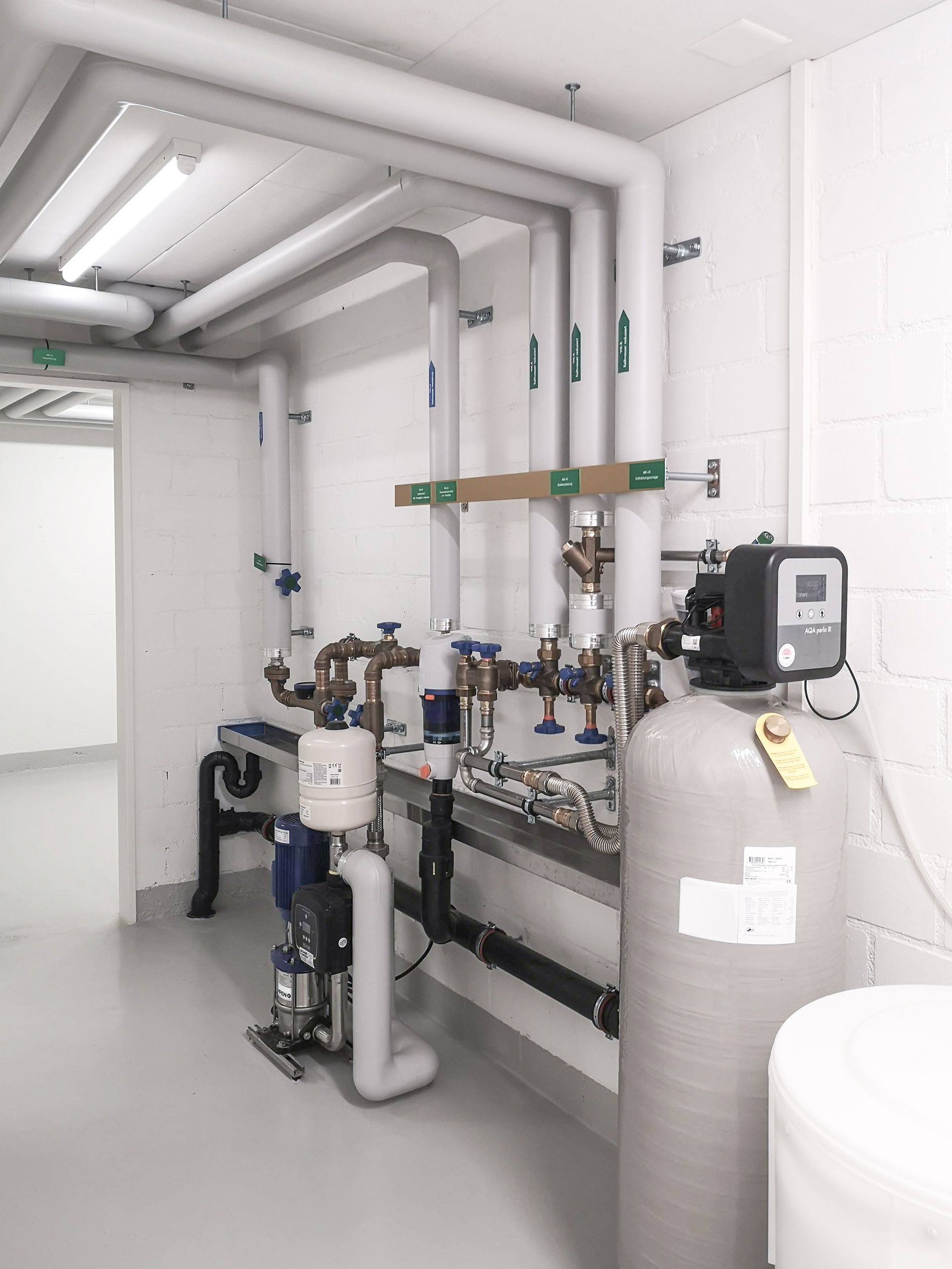 Industrial water treatment room with pipes, tanks, and filtration equipment in a white utility space Industrial water treatment room with pipes, tanks, and filtration equipment in a white utility space