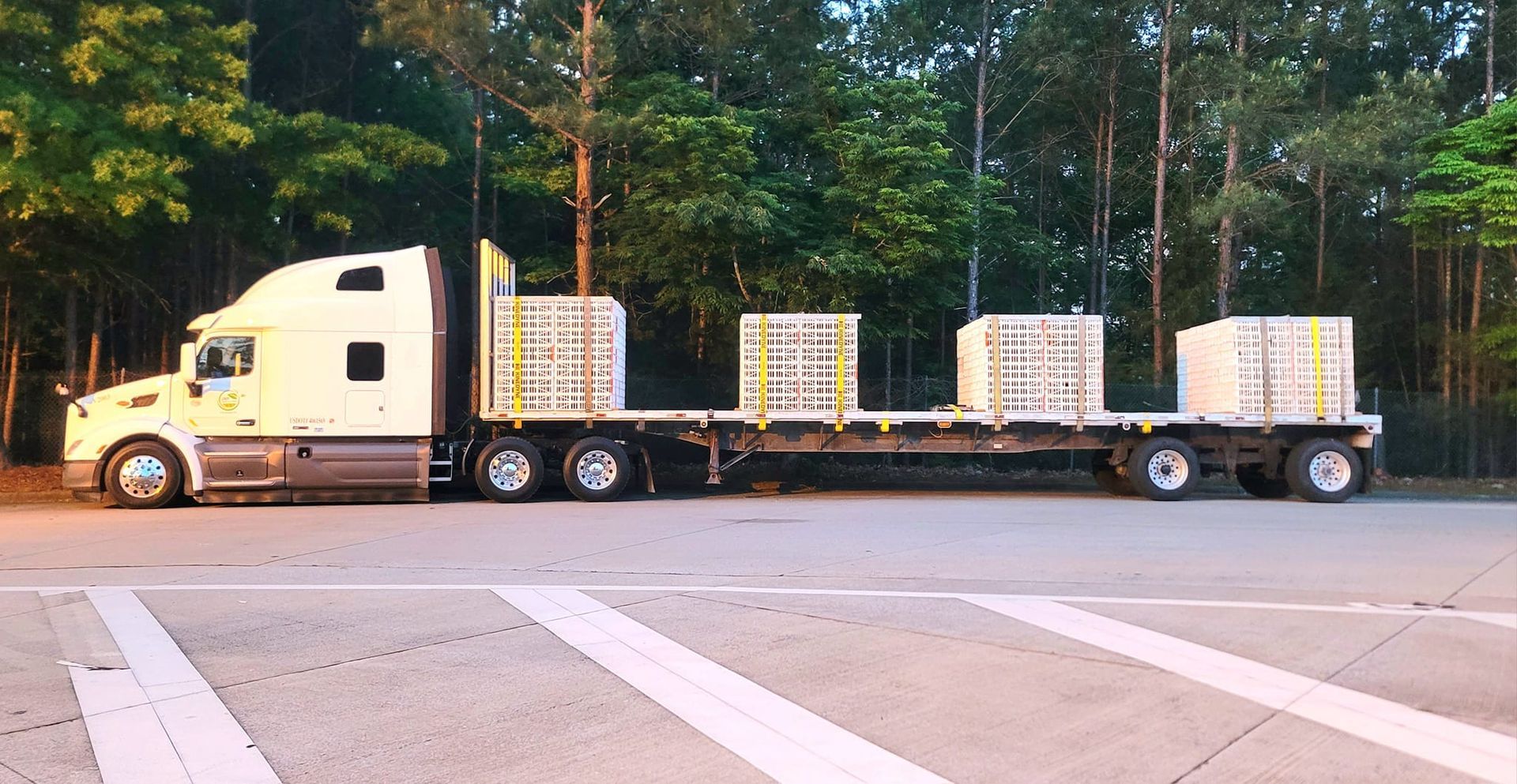 A semi truck with a flatbed trailer is parked in a parking lot.