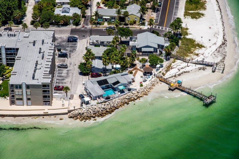An aerial view of a beach with a dock and buildings