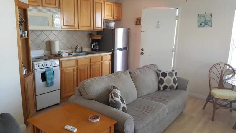 A living room with a couch , table , chairs and a kitchen.