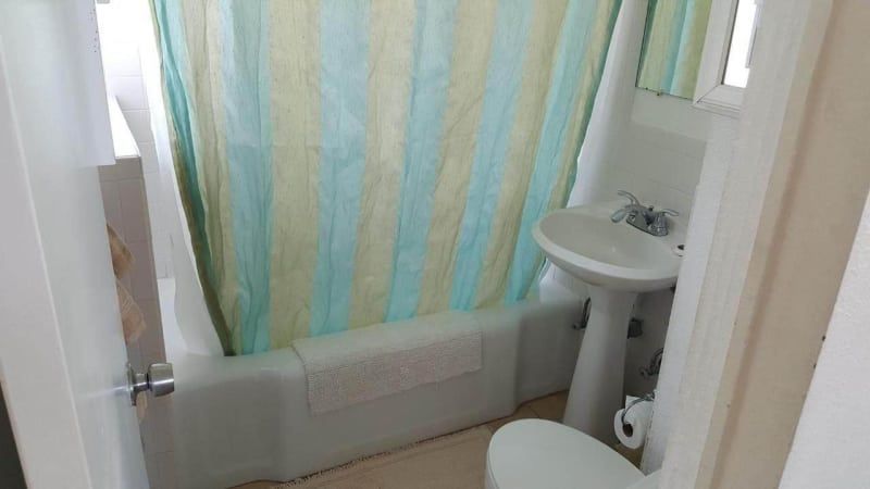 A bathroom with a toilet , sink , and shower curtain.