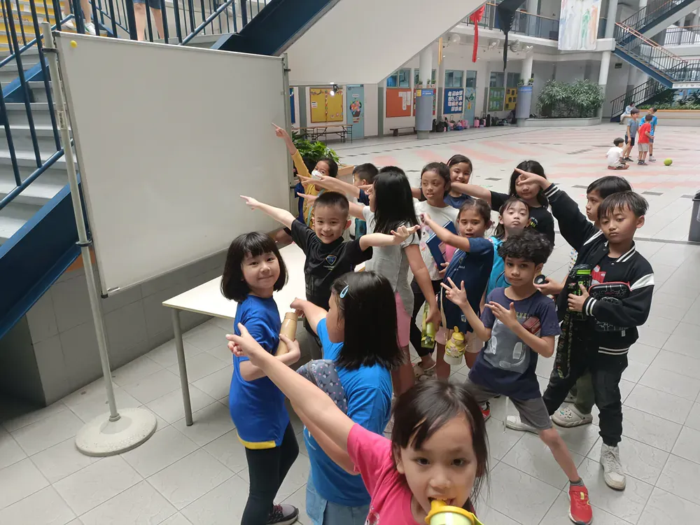 A group of children are standing in a room with their arms outstretched.