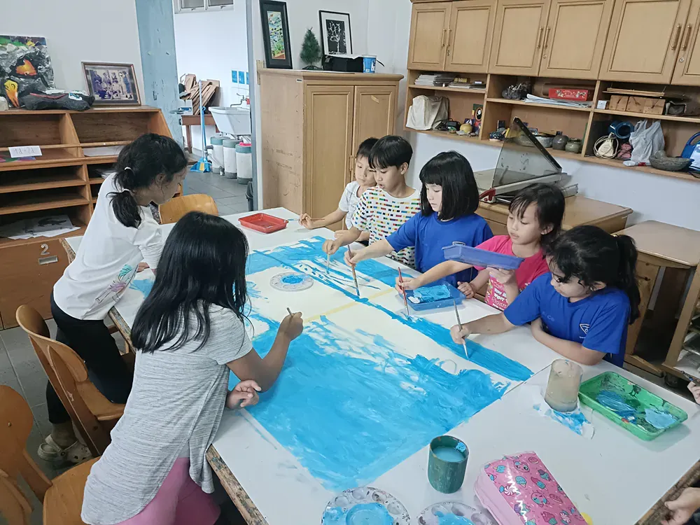 A group of children are sitting around a table painting.