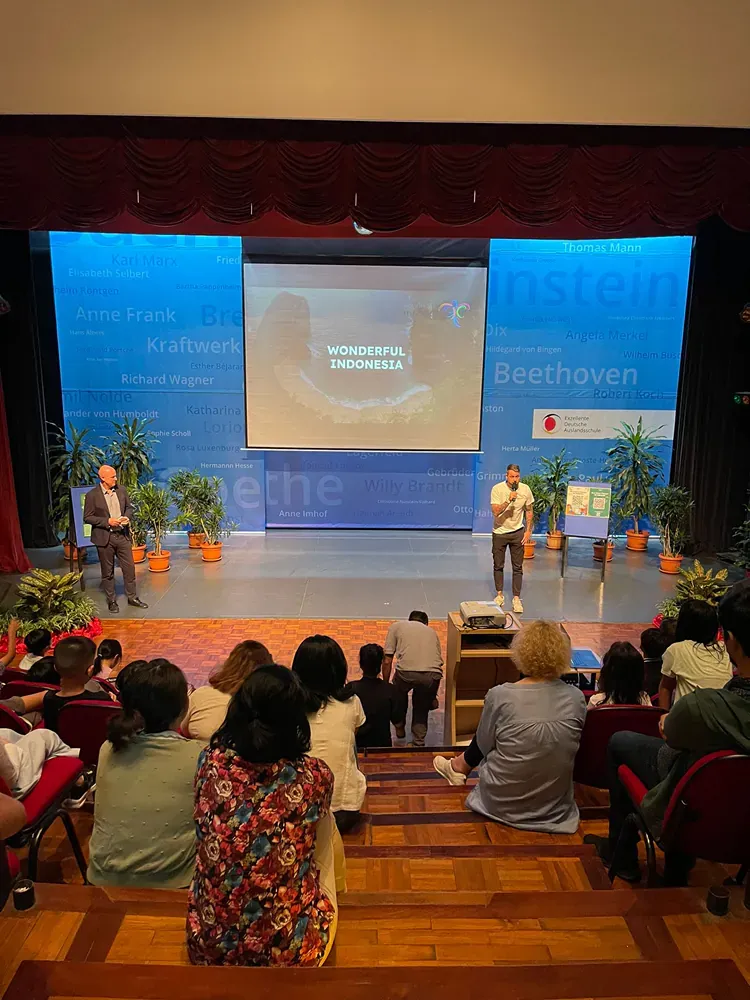 A man is standing on a stage giving a presentation to a group of people.