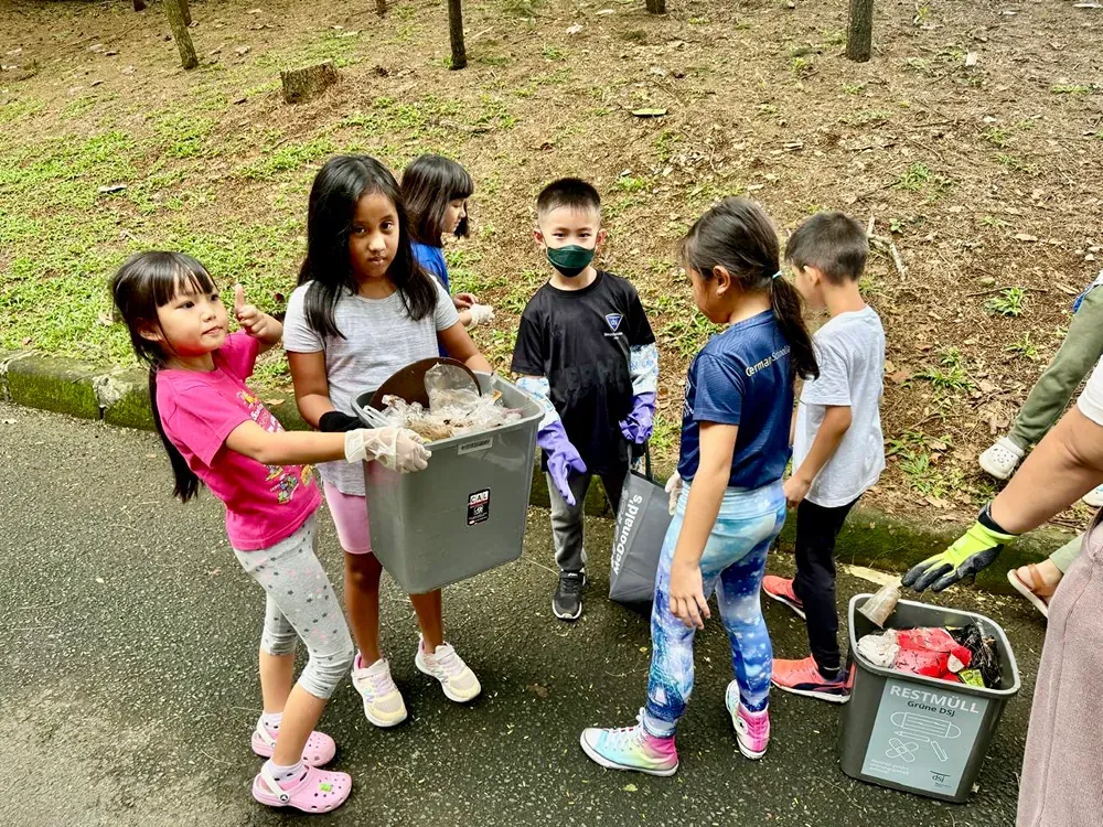 A group of children are standing next to each other on a sidewalk.