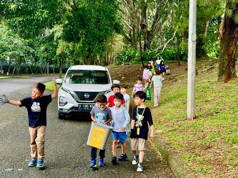A group of children are walking down a sidewalk next to a car.