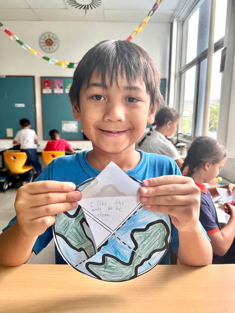 A young boy is holding a piece of paper with a picture of the earth on it.