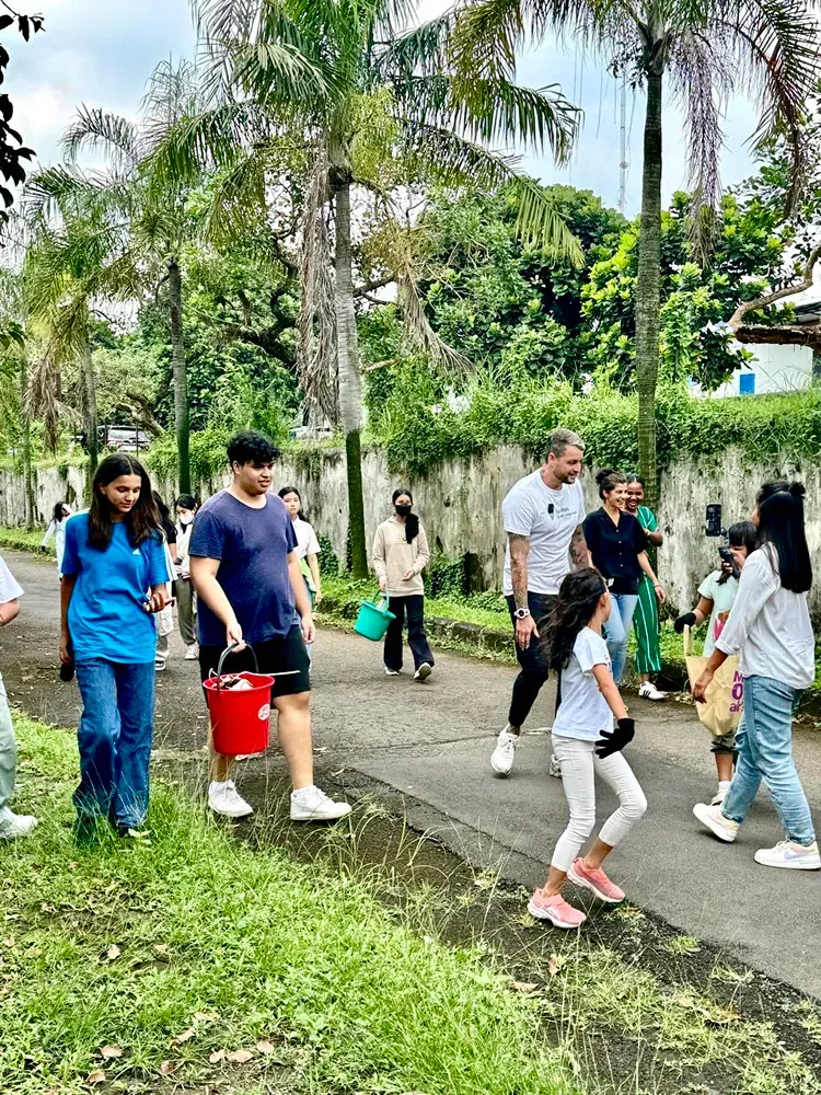 A group of people are walking down a street holding buckets.