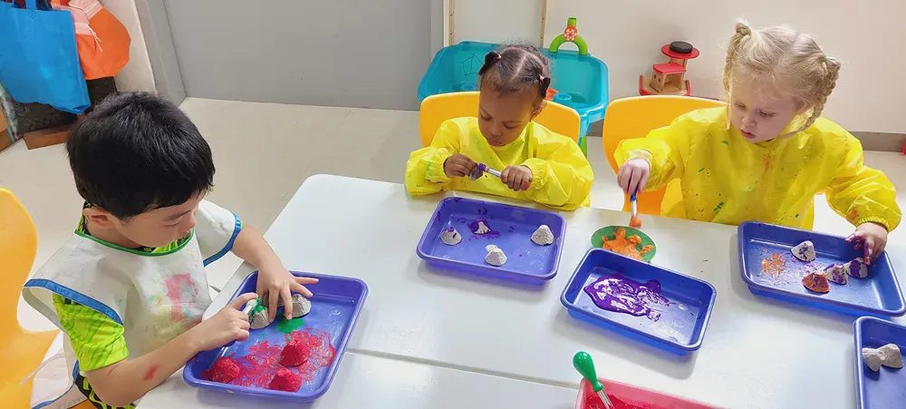 A group of children are sitting at a table playing with sand.