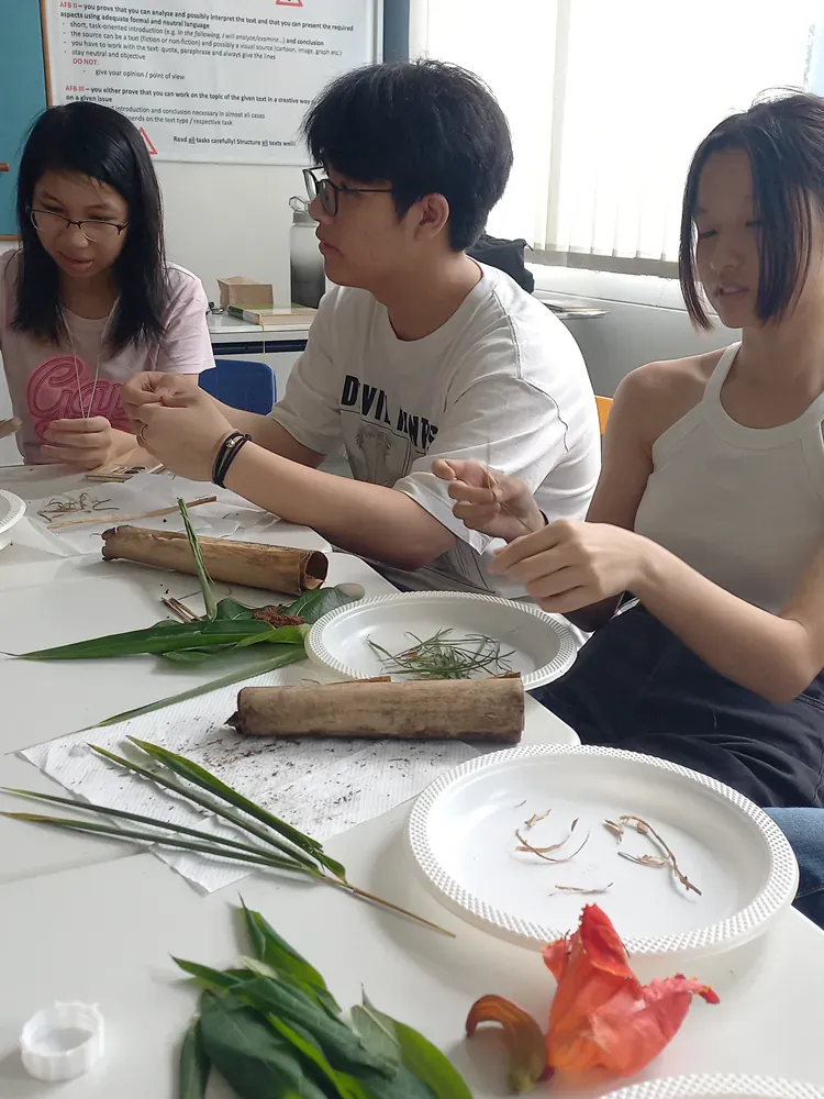 A group of people are sitting at a table with plates of food and plants.