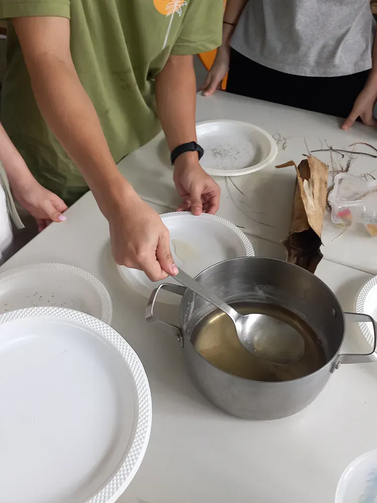 A person in a green shirt is preparing food in a pot
