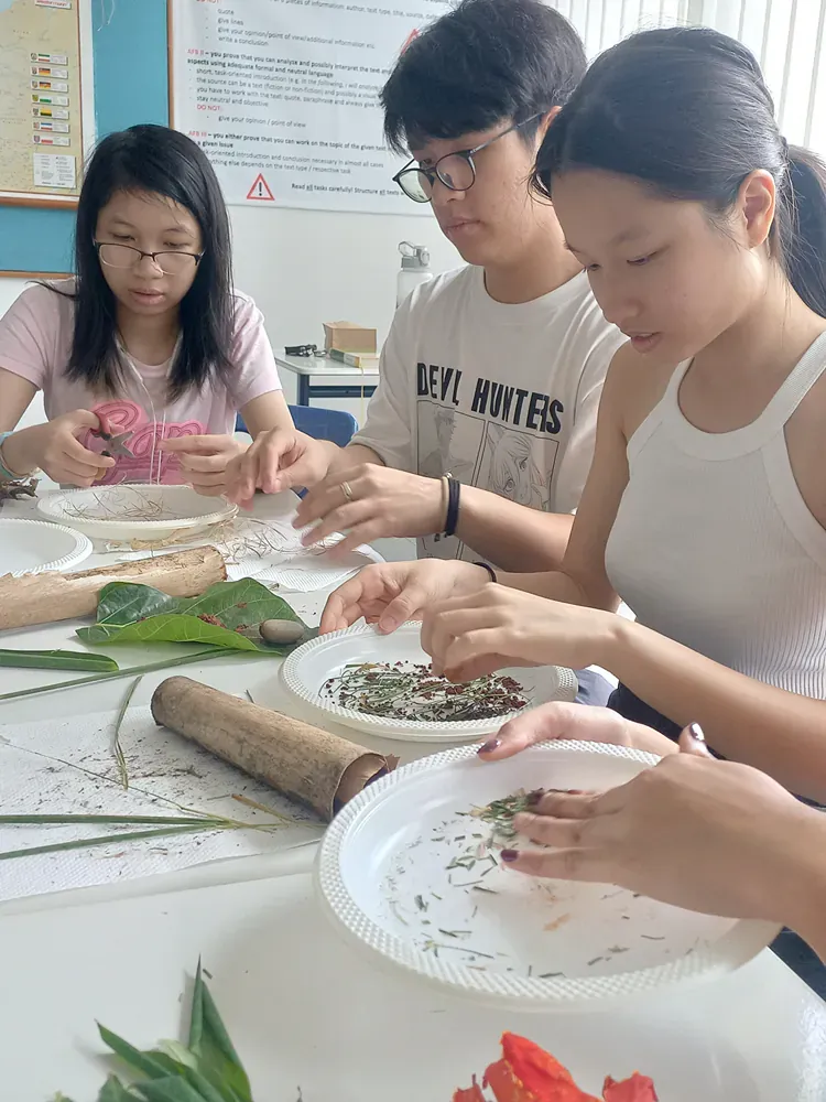 A group of young people are sitting at a table making crafts.