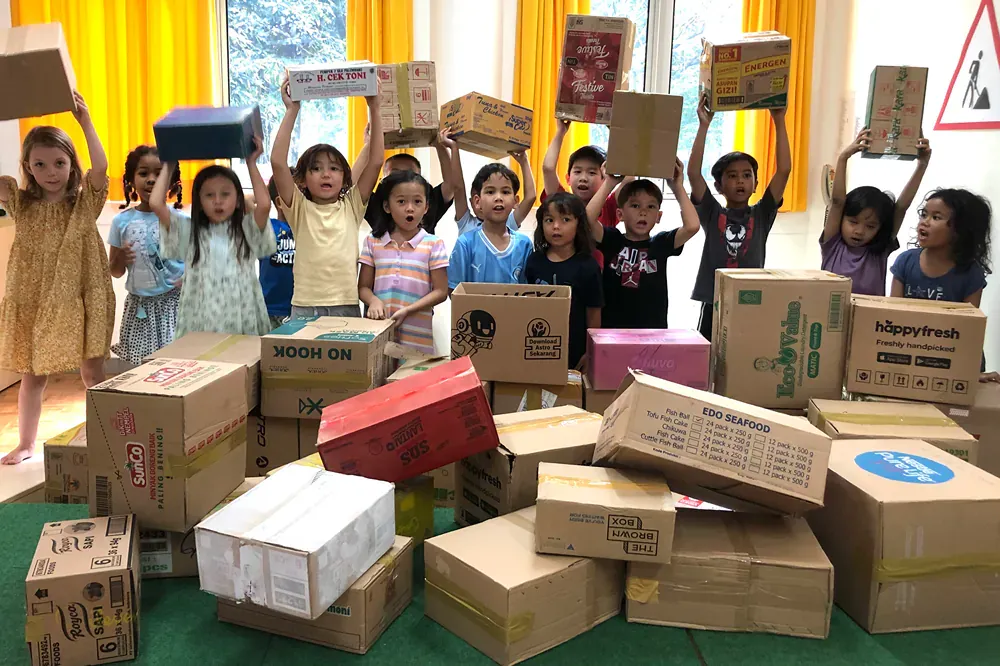 A group of children are standing in front of a pile of cardboard boxes.