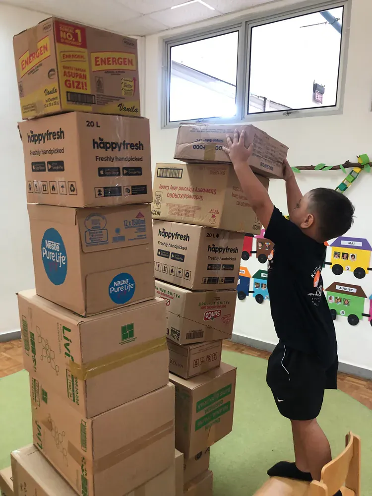 A young boy is stacking boxes on top of each other in a room.