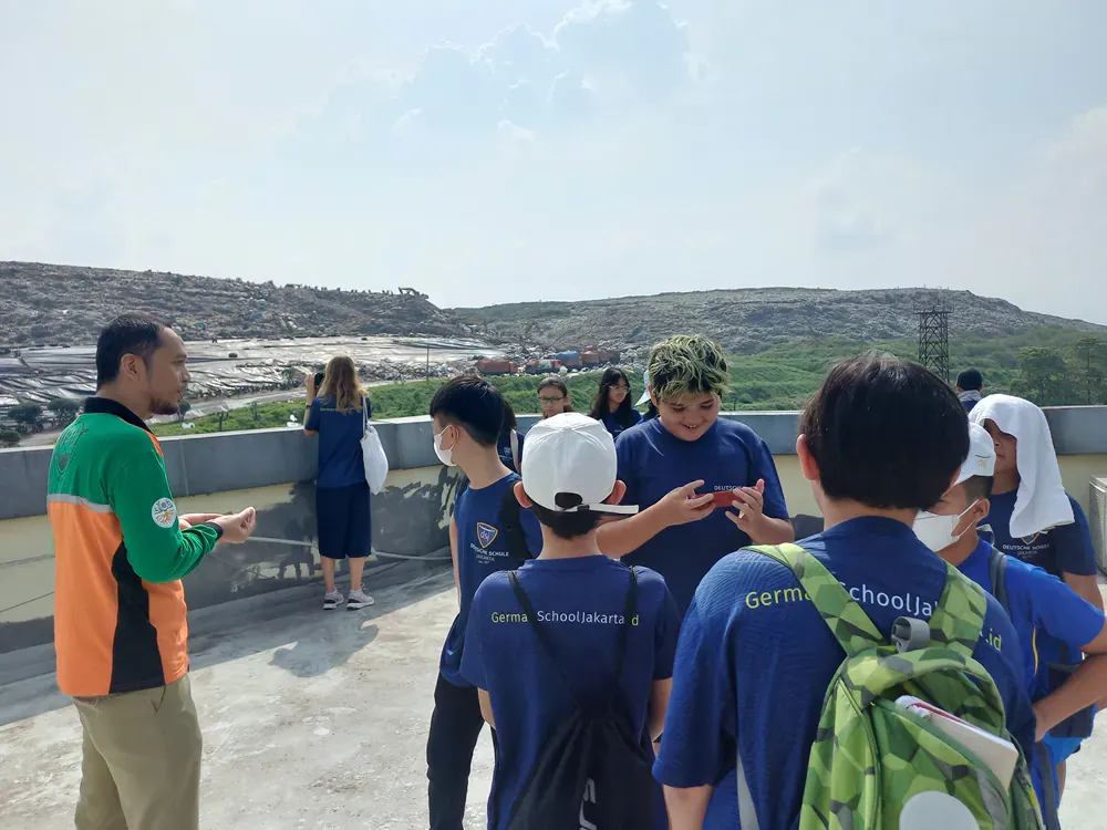 A group of children are standing on a balcony talking to a man.