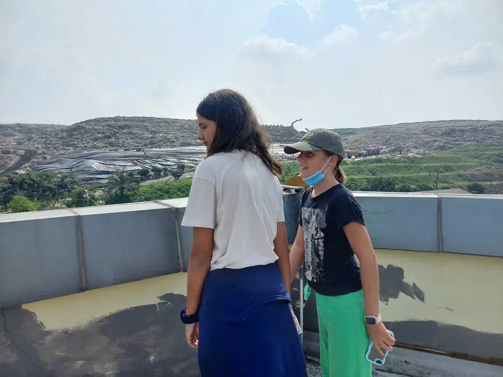Two young girls are standing next to each other on a rooftop.