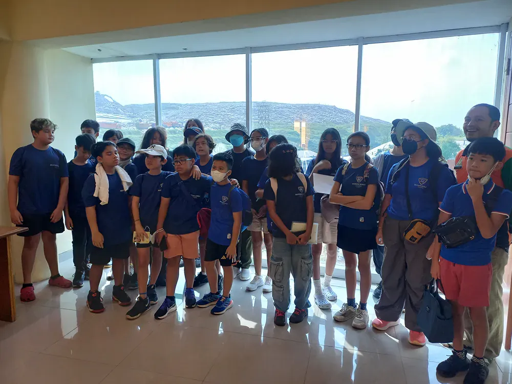 A group of children are standing in front of a window.