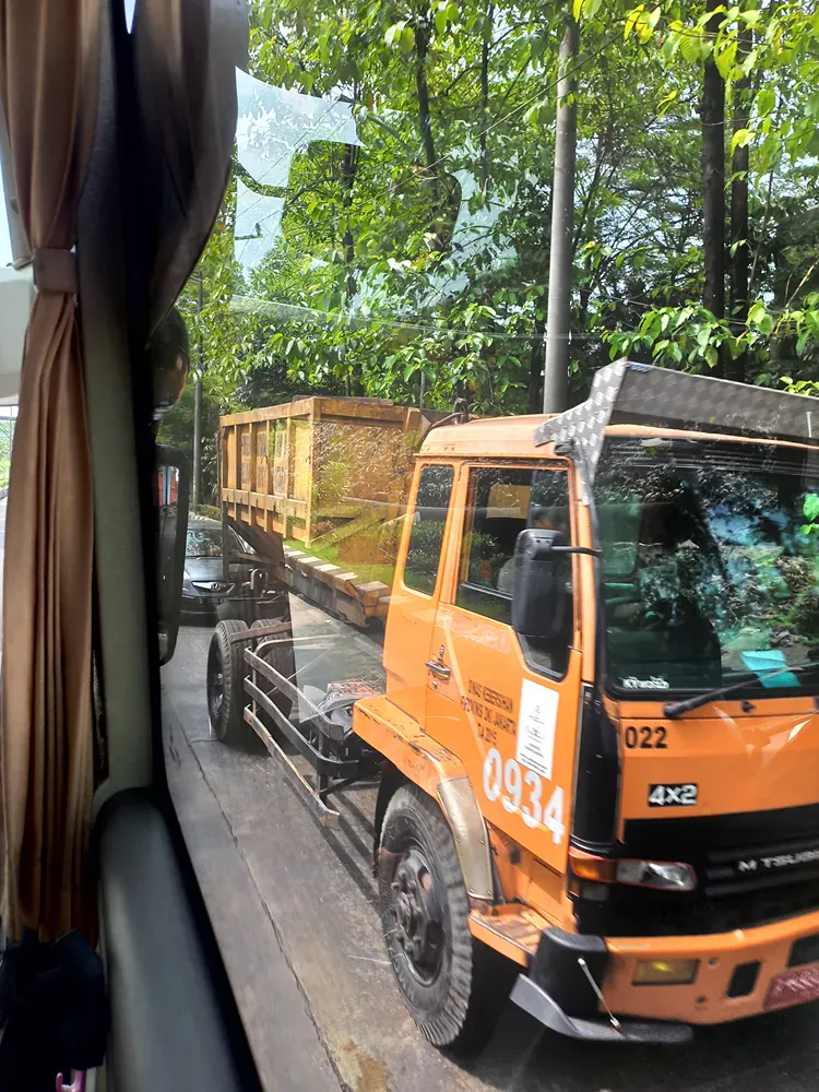An orange truck with the number 0934 on the front is parked on the side of the road.