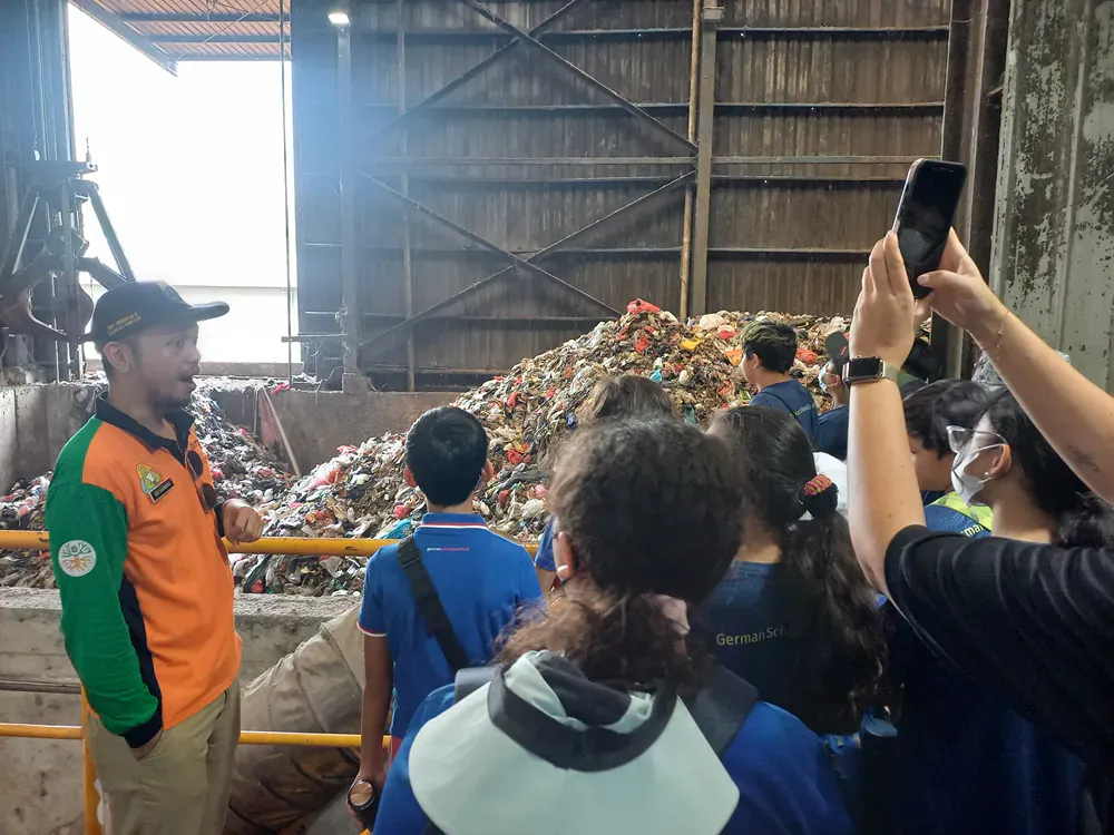 A group of people are standing in front of a pile of trash.