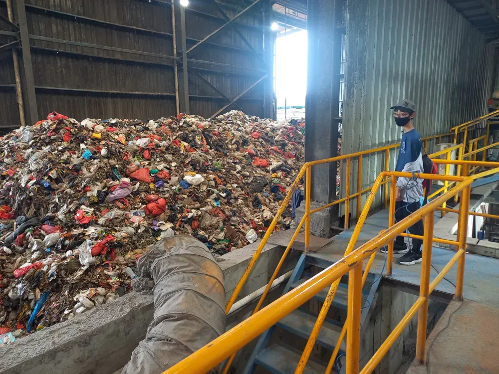 A man in a mask is standing in front of a pile of trash.