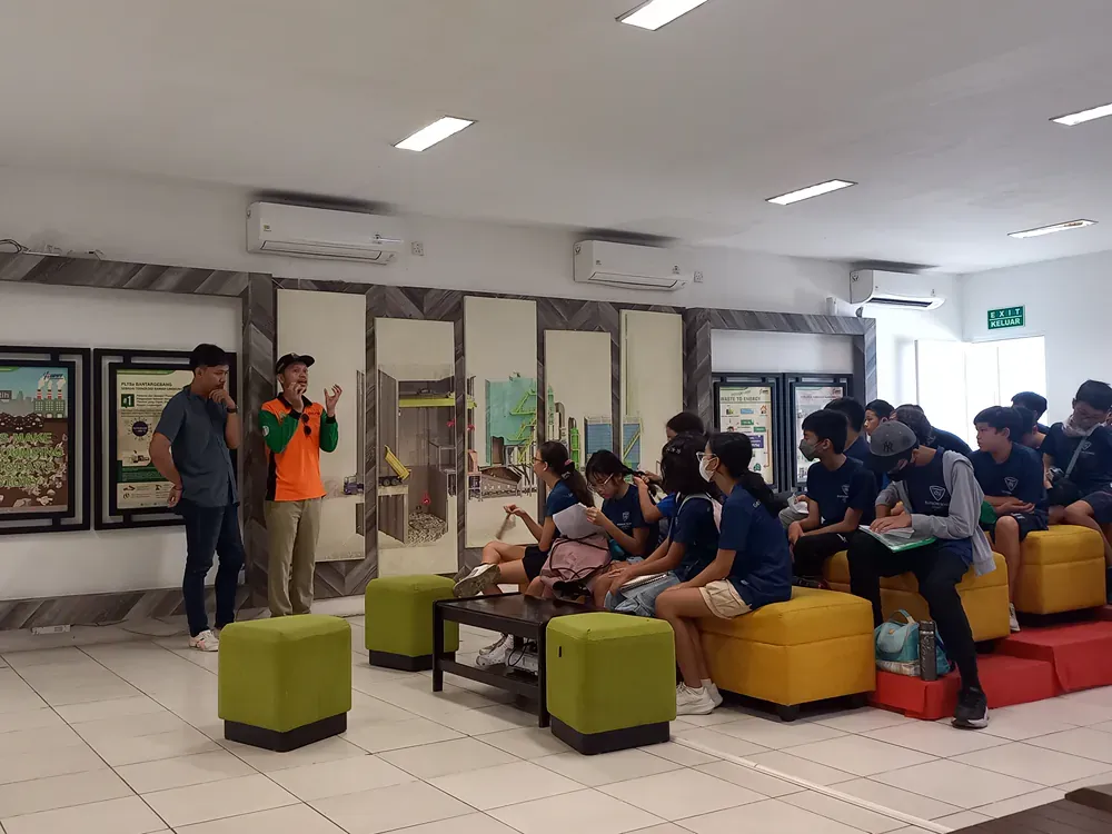 A group of people are sitting on ottomans in a room.