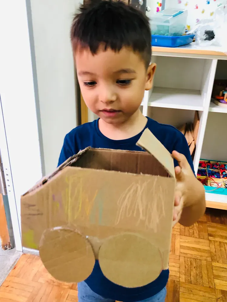 A young boy is holding a cardboard box in his hands.