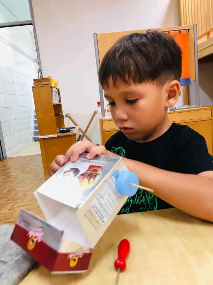 A young boy is playing with a cardboard box
