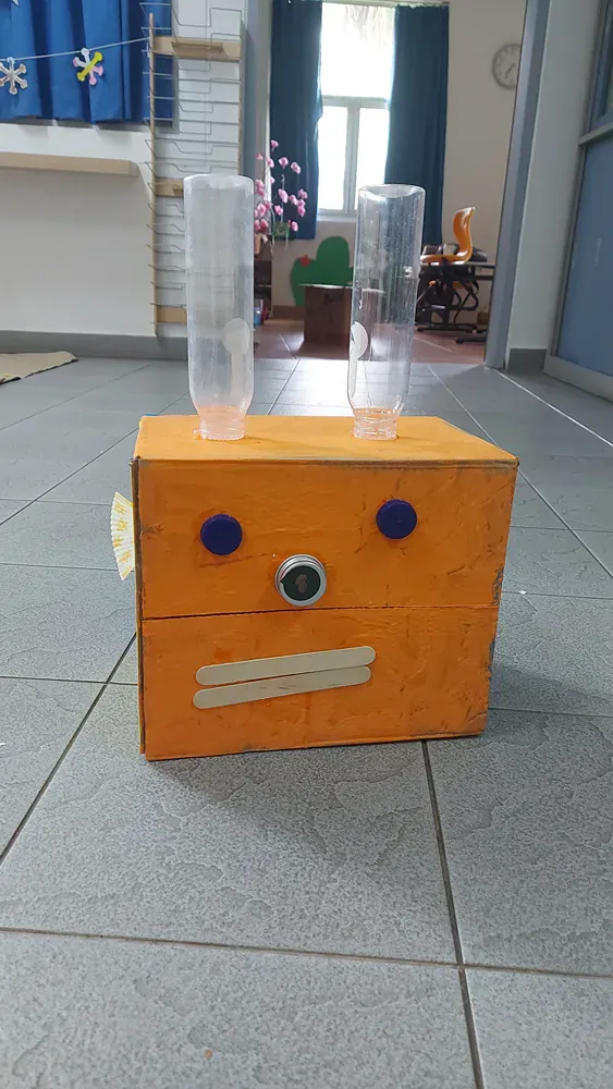 A wooden box with a face on it is sitting on a tiled floor.